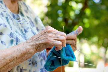 Pensioner woman knitting socks for her grandchildren, retiree lifestyle concept, enjoys in retirement