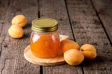 Glass Jar of Homemade Tasty Apricot Jam and Ripe Apricots on the Wooden Background Horizontal