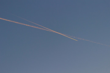 Two tracks from the plane to meet each other against the dark blue sky.