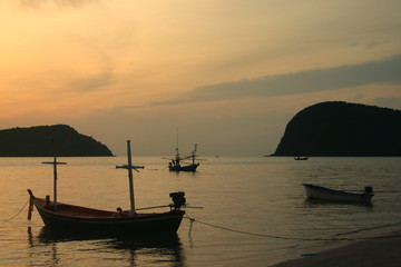 Thai fishing boat used as a vehicle for finding fish in the sea on sunset background.