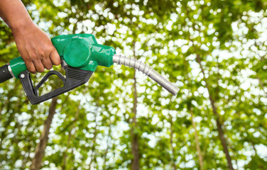 Naklejka premium Green conservation. Gas pump nozzle and leaf background. Fuel dispenser on nature background. energy conservation of Nature Concept.