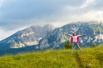Fototapeta premium happy European girl stands on background of Montenegro mountains in Durmitor park, with copy space