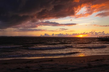 Dramatic sunset through a cloudy dark sky over the ocean.