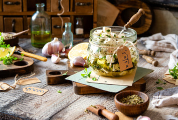 homemade marinated diced cheese feta in glass jar with herbs, garlic, basil