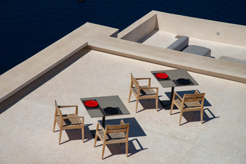 Typical terrace with tables and chairs for breakfast or coffee break on the island of Santorini, Greece, Europe. Color and design with a direct view of the caldera gulf.