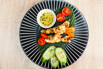 round plate with thai food on table chicken vegetables and sauce top view