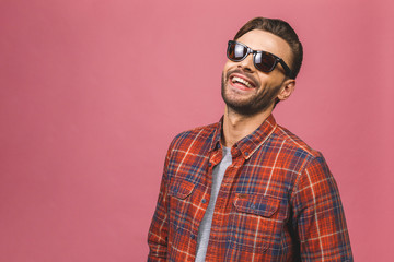 Obraz premium Portrait of a handsome happy cool young man in sunglasses enjoying over pink background.