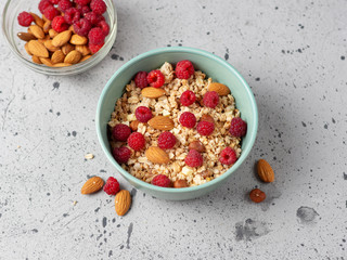 Muesli for Breakfast with nuts and raspberries. Almonds and hazelnuts . Grey concrete table