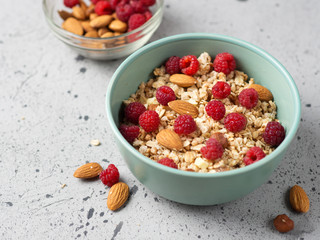 Muesli for Breakfast with nuts and raspberries. Almonds and hazelnuts . Grey concrete table