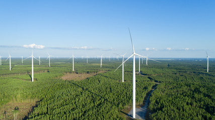 Wind turbine near green forest, beautiful aerial landscape with blue sky.  Alternative energy...
