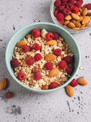 Muesli for Breakfast with nuts and raspberries. Almonds and hazelnuts . Grey concrete table