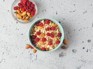 Fototapeta na wymiar Muesli for Breakfast with nuts and raspberries. Almonds and hazelnuts . Grey concrete table