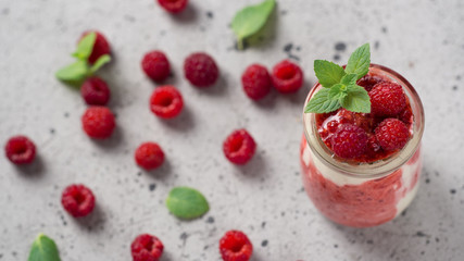 Raspberry cold summer cream dessert parfait on a grey table with mint