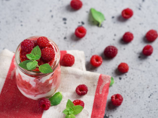 Raspberry cold summer cream dessert parfait on a grey table with mint