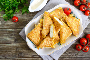 Tasty fried puff patties from thin Armenian lavash on a wooden table. Envelopes from pita bread cottage cheese filling. Top view, flat lay.