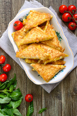 Tasty fried puff patties from thin Armenian lavash on a wooden table. Envelopes from pita bread cottage cheese filling. Top view, flat lay.