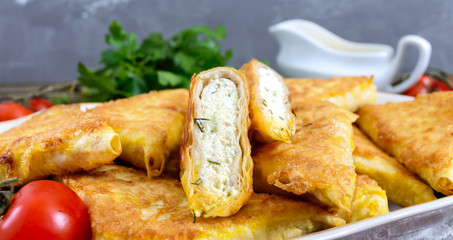 Tasty fried puff patties from thin Armenian lavash on a wooden table. Envelopes from pita bread cottage cheese filling.