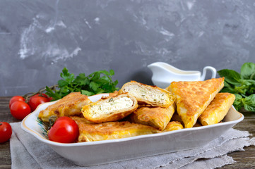 Tasty fried puff patties from thin Armenian lavash on a wooden table. Envelopes from pita bread cottage cheese filling.