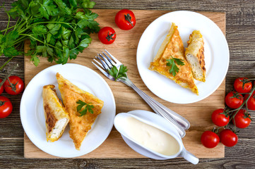 Tasty fried puff patties from thin Armenian lavash on a wooden table. Envelopes from pita bread cottage cheese filling. Top view, flat lay.