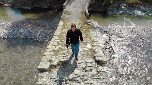 Aerial view of a person crossing a stone bridge