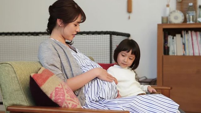 Close up of child touching pregnant mother belly
