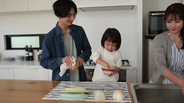 Little girl cleaning bowls with parents
