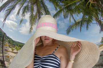Women on the beach wearing a big hat, covering the sun - 281813355