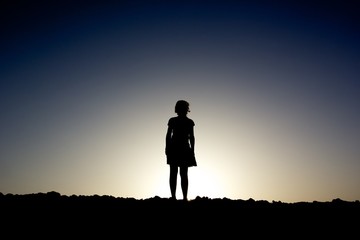 Silhouette of a girl standing on a hill