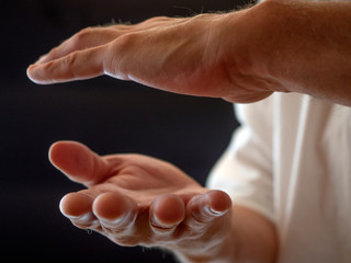 Human hand training in karate, tai-chi, martial arts. White shirt on black background.