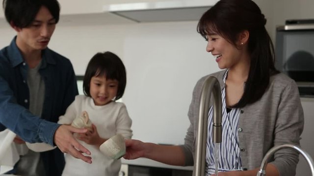 Little girl cleaning cups with parents
