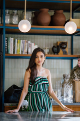 Portrait of a beautiful, elegant, young and attractive Indian Asian woman in a green outfit smiling as she poses in the trendy interior of her home on a morning.