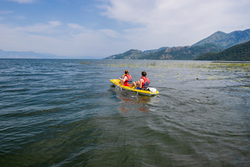 Tourists couple in canoe on the lake Lake with mountains in Skadar National Park in Montenegro