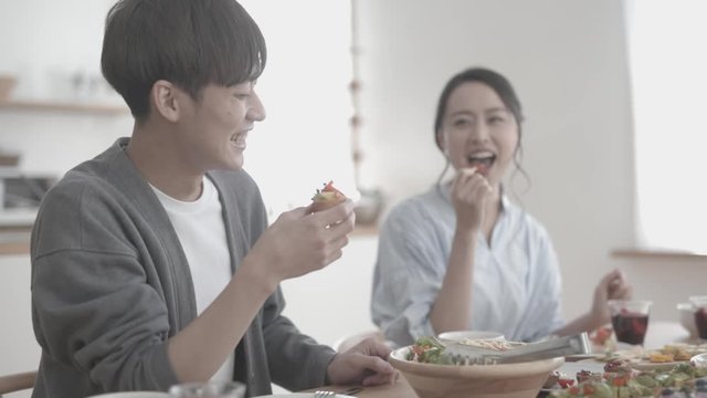 Young couple eating, talking and laughing at home
