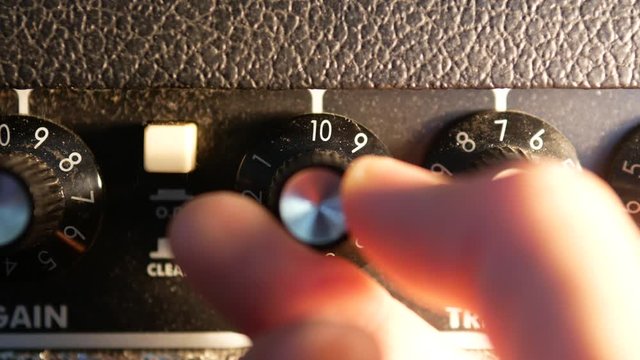 Men hand turning the volume knob on guitar amplifier