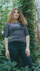 Satisfied woman looking dreamily standing in green Park. woman posing in the woods