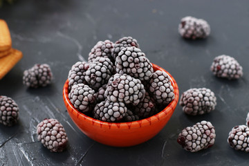 Freshly frozen blackberries in a bowl against a dark background, freezing berries for the winter
