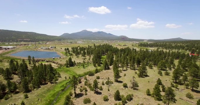 Aerial pill back from an isolated pond to the ponderosa​ pines near Williams, Arizona. Concept: Southwestern US, railroad, ​transportation