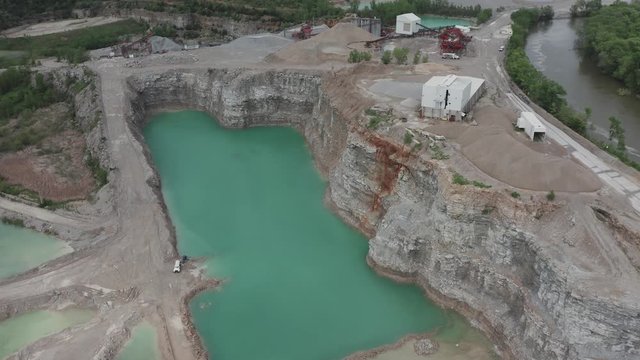 Drone flyover a quarry in the Midwestern, USA.  Birds of prey circle on the quarry cliffs below.  in summer, in 4K.