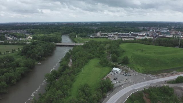 Drone rises over river and looks toward a highway and a small Midwestern city in the distance.  in summer, in 4K.