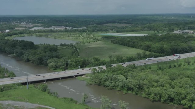 Drone flies towards a midwestern highway in the USA as it crosses over a muddy river in the summer.  in 4K.