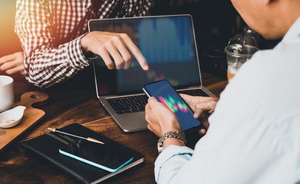 Two Businessman holding smartphone pointing and look directions change Average line Share price movement Stock trading in the up and down on display