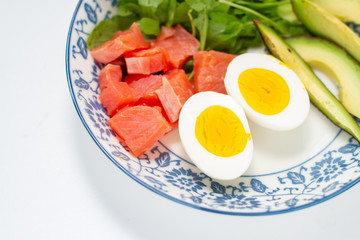arugula leaves, egg halves and red fish in a plate