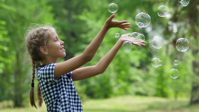 Girl playing with soap bubbles outdoor. The nine-year-old girl plays with soap bubbles in the summer garden.