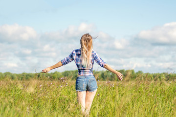 happy beautiful girl in the blooming field enjoying the sun and flowers