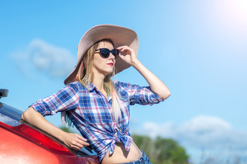 Portrait of romantic beautiful girl in black glasses and big hat. blue sky in background