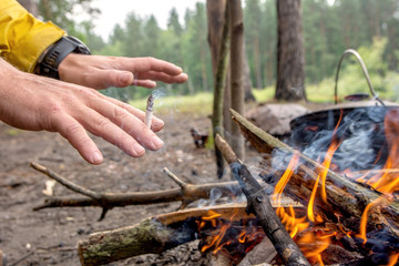 man warms hands near campfire in the forest.