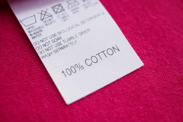 White laundry care washing instructions clothes label on red cotton shirt