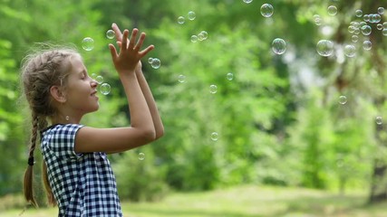 Girl playing with soap bubbles outdoor.