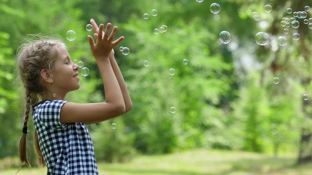 Girl playing with soap bubbles outdoor.