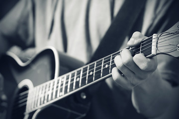 Black and white image, where the musician plays a melody on an acoustic guitar, holding a hand...